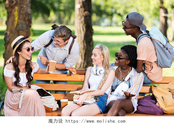 学生们在公园里进行交流多民族学生坐在公园长椅上